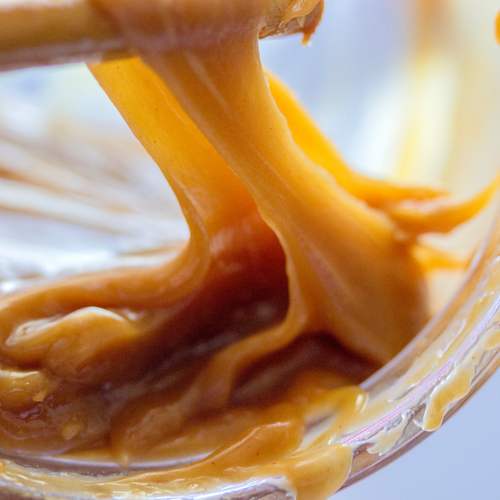 Gooey Caramel being scooped up from a jar