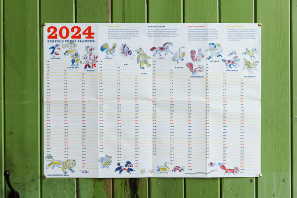 2024 Penfold Press planner displayed on a wooden panel