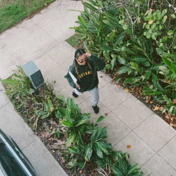 Girl in braids wearing an oversized green hoodie fashion blogger photography with plants in the background college style aesthethic 