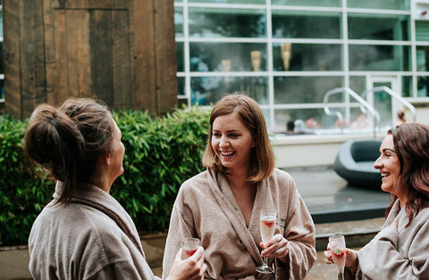 Ladies in robes outside at spa enjoying drinks