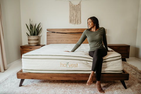 Lady sitting on the edge of her Harvest Green mattress in her room.