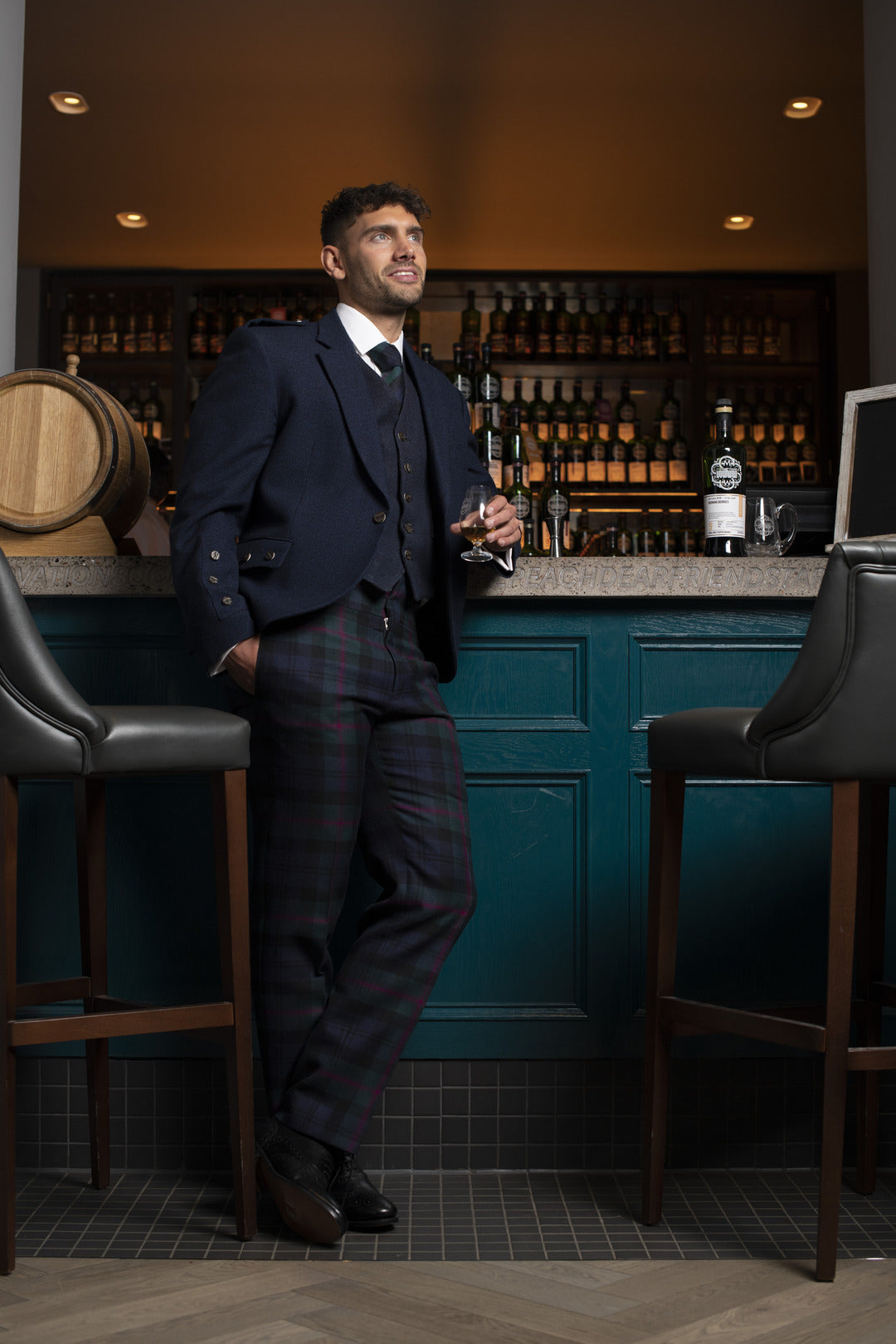 an at bar wearing tartan trews and drinking whisky