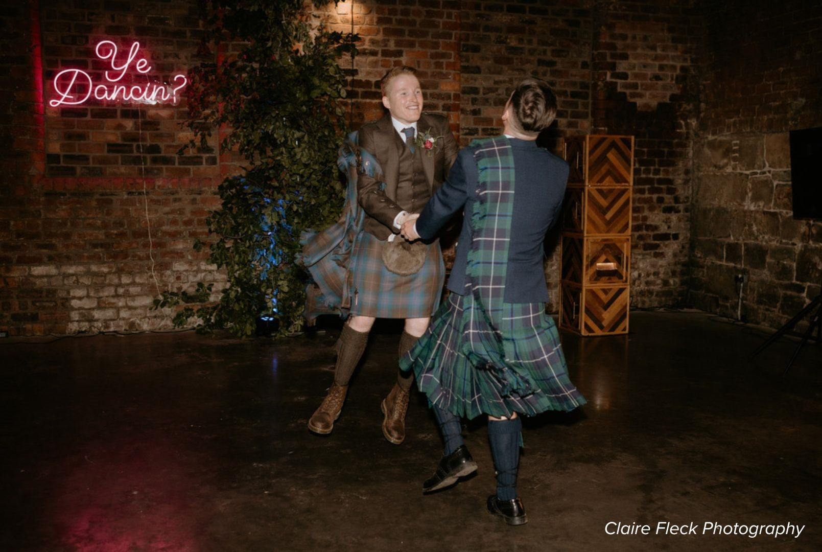 grooms dancing in highlandwear on their wedding day