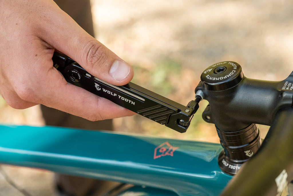 A cyclist uses the Wolf Tooth 8-Bit Pack Pliers to adjust their bike's stem.