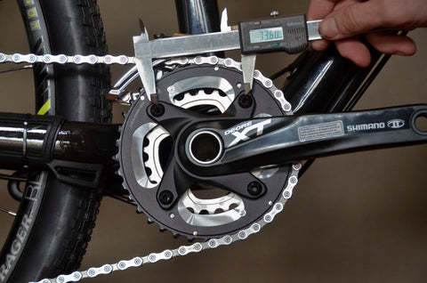 A caliper measuring the distance between two adjacent bolts on a chainring on a bicycle