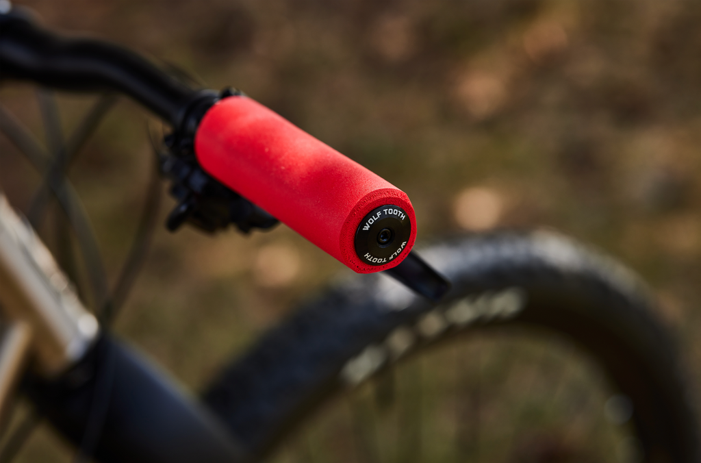 A red Wolf Tooth Fat Paw grip with Wolf Tooth alloy bar end plugs.