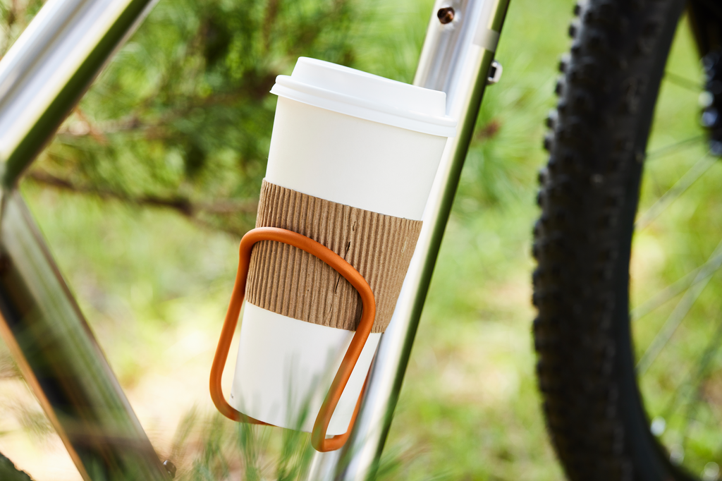 A Wolf Tooth Morse Cage Ti in Limited Edition Pumpkin Spice Latte with a latte placed inside of the cage instead of a bottle.