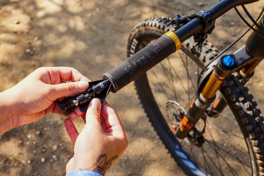 A pair of hands removes an EnCase System Bar Kit One from the inside of a Wolf Tooth Echo Lock-On Grip, showing that the grip is compatible with the EnCase System.