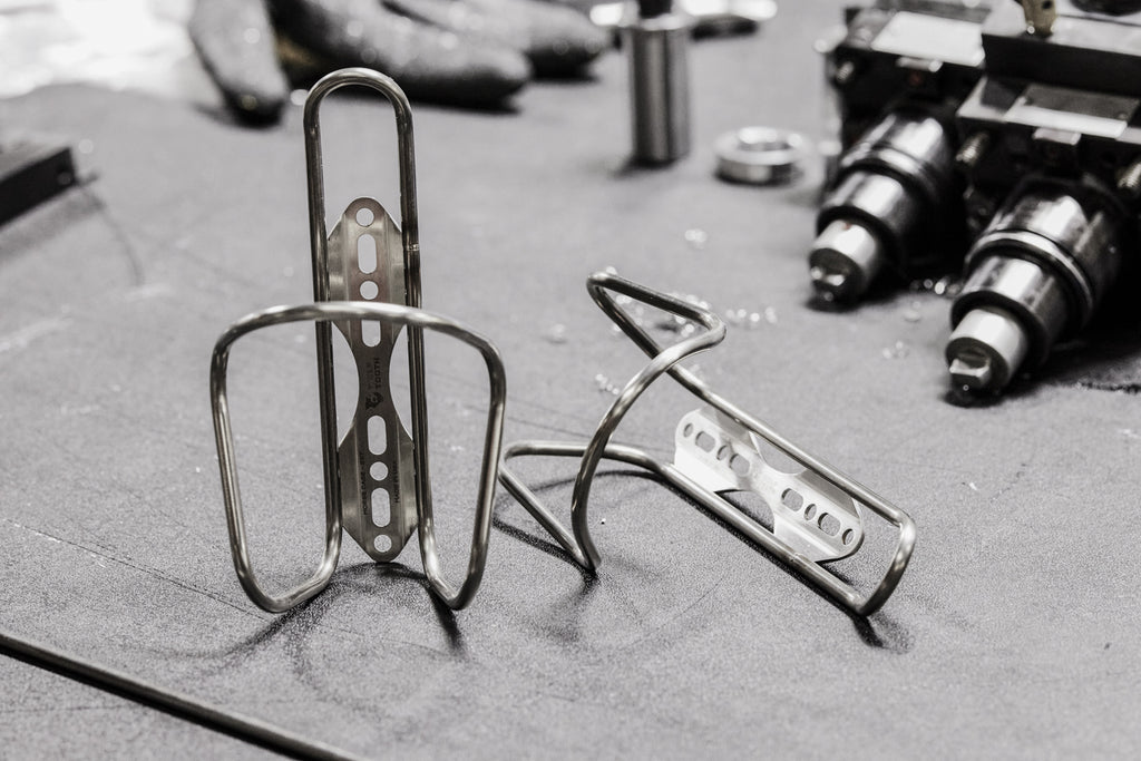 Two Wolf Tooth Morse Cage Stainless Steel rest on a workbench surrounded by machine shop tools.