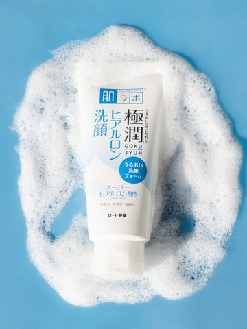 Hada Labo Gokujyun Hyaluronic Acid Foaming Cleanser นอนอยู่บนพื้นพร้อมรูปถ่ายสไตล์ไลฟ์สไตล์โฟมบนพื้นหลังสีน้ำเงิน reviewラボ 極潤 ヒアルロン洗顔フォーム