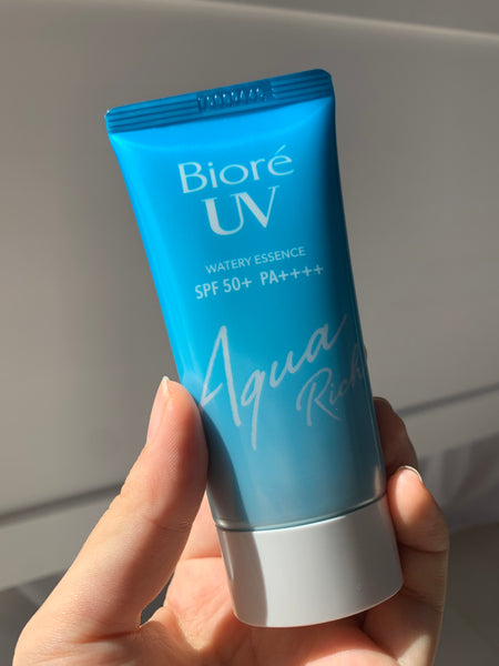 holding new biore uv aqua rich watery essence japanese suncreen with clear quality background ビオレ uv アクアリッチ ウォータリーエッセンス