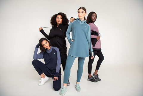 Four women wearing different activewear and posing in front of a white background