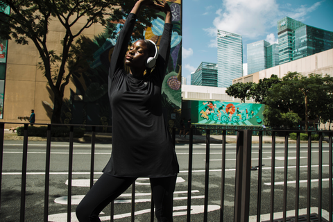 Woman wearing headphones and stretching outdoors