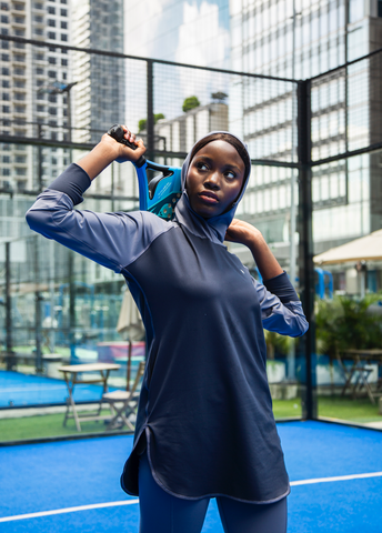 A woman stretching holding a racket in a court