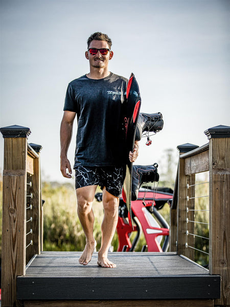 Nic Rapa walking on dock towards photographer with wakeboard under arm