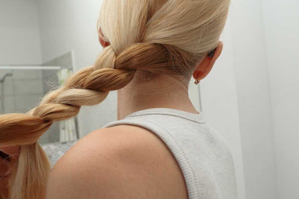 blonde woman braiding her hair