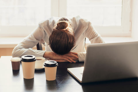 Woman at work stressed out and laying head on computer. 