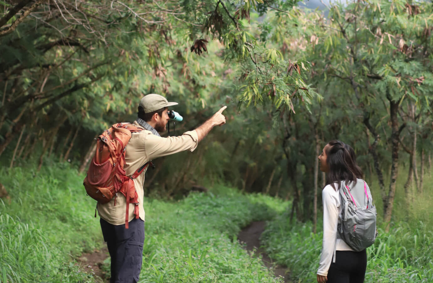 Peter Thoene pointing something out in a forest to a girl, while holding Nocs