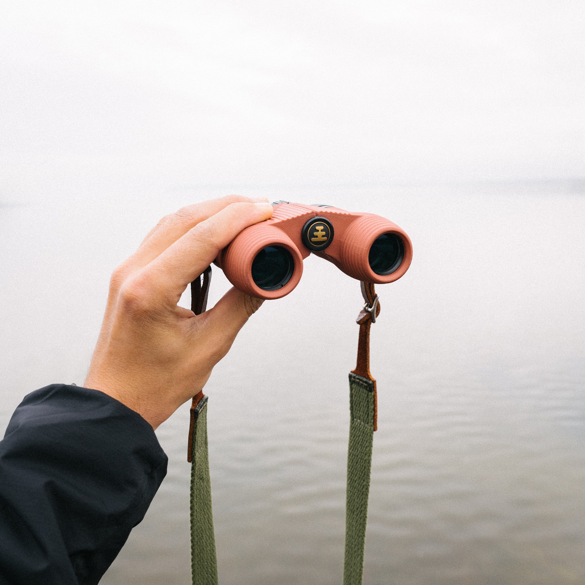 Person looking through Nocs compact waterproof and fogproof binoculars in a wet and foggy setting