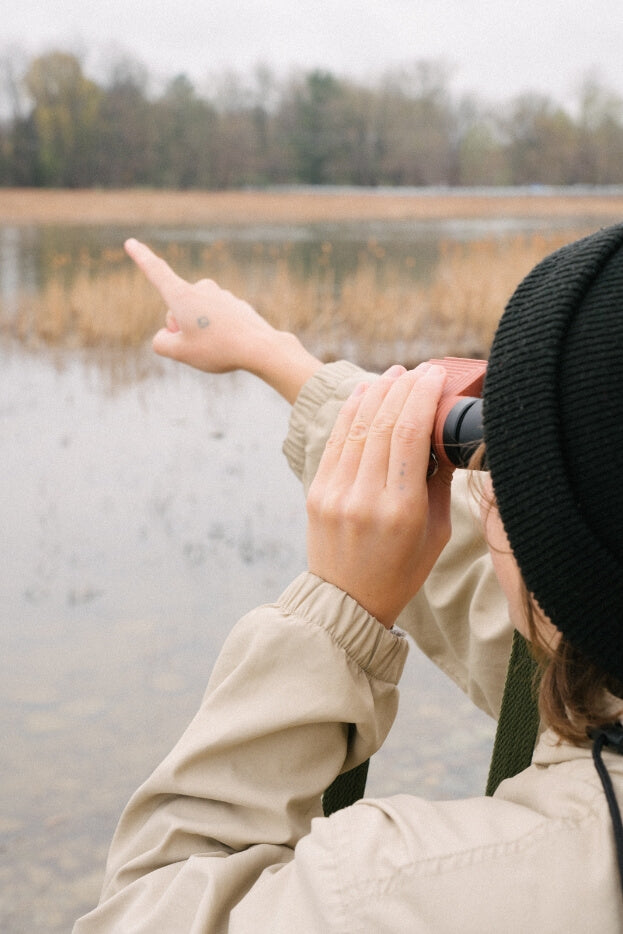 Daniel Schechner pointing into the distance while looking through Nocs Stanrd issue 8x25 binoculars