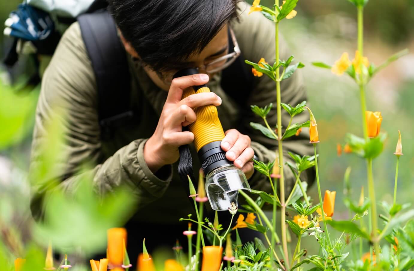 Mary Tolosa looking through a monocular into some plantlife