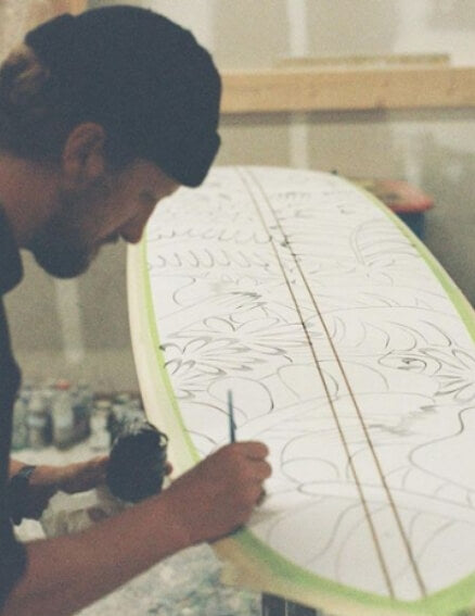 Man drawing some art onto a surfboard
