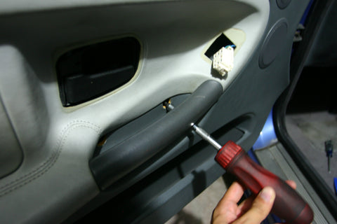 Unscrewing the screws that hold the door card to the door.