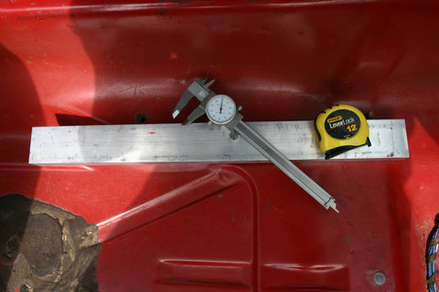 Aluminum bar stock in the chassis with dial calipers and a tape measure resting on it.