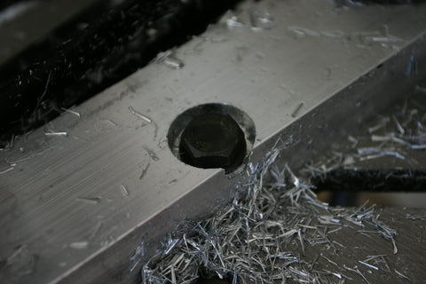 Completed counterbore in aluminum bar stock with bolt inserted in the hole to verify that the head of the bolt fits within the counterbore and is not proud of the top surface of the aluminum bar stock.