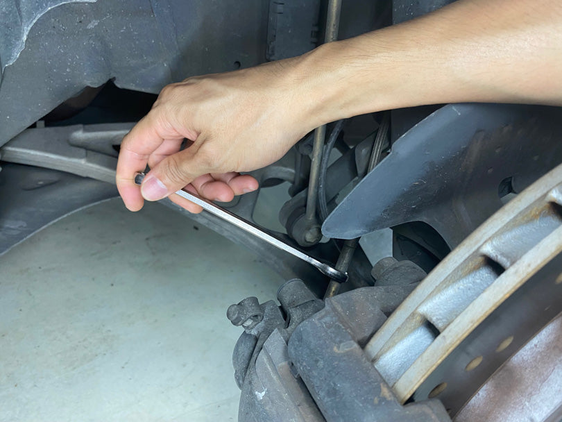 Loosening the brake hose with a wrench.