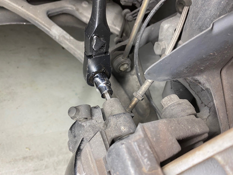 Removing the caliper guide pins with a hex-bit socket.