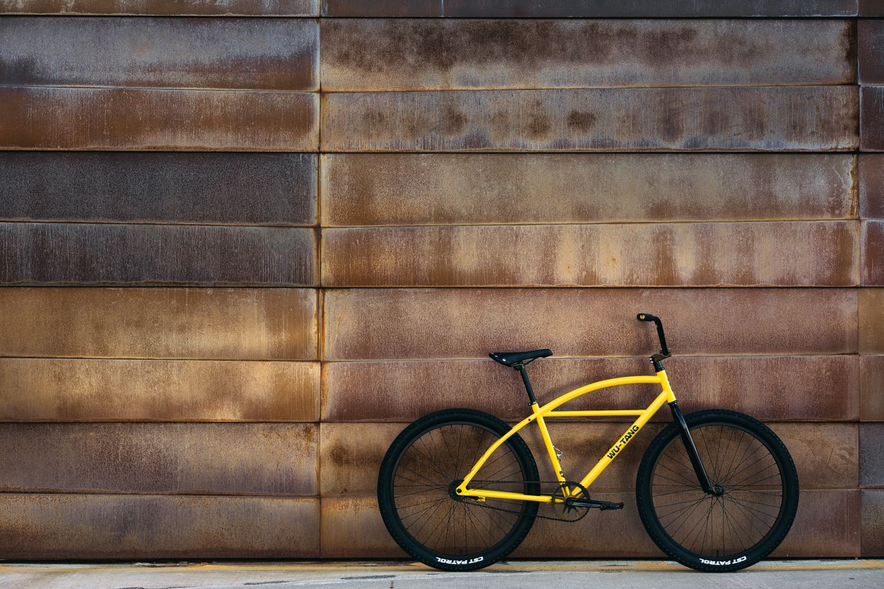 Yellow and Black bicycle leaned against a rustic wall 