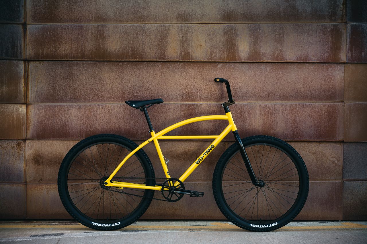 Yellow and Black bicycle leaned against a rustic wall 