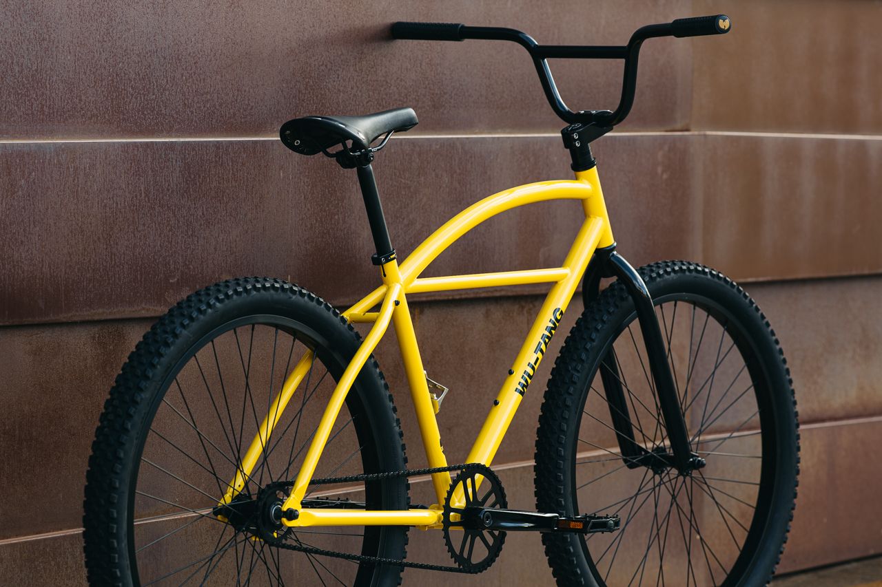 Yellow and Black bicycle leaned against a rustic wall 