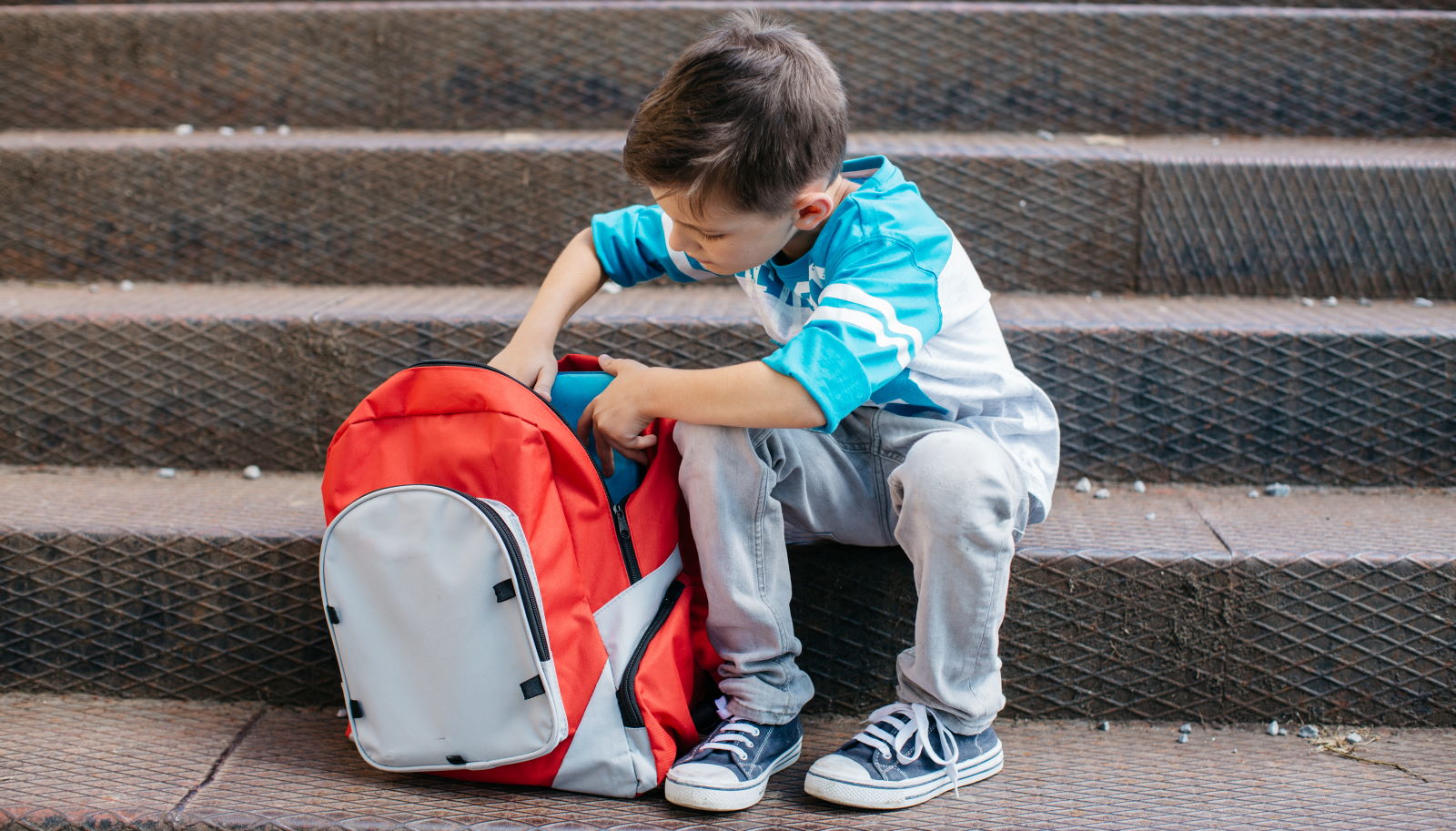 Enfant assis avc son cartable posé à terre