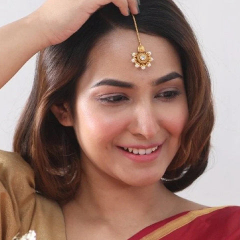 A picture of a woman with short hair, wearing a maang tikka