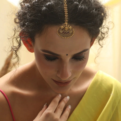 An image of a woman showcasing a maang tikka.