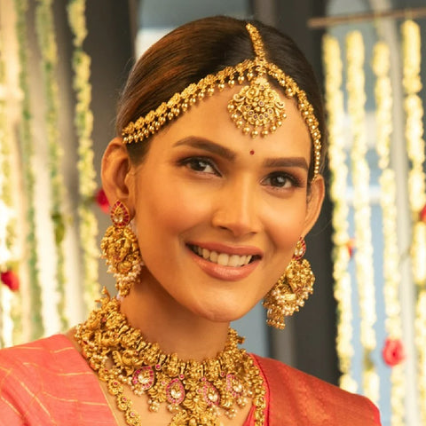 An image of a bride in a bridal attire with an antique damini maang tikka