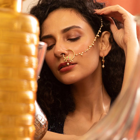 An image of a woman in front of the mirror, wearing an enamel nose ring.