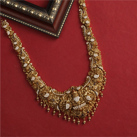 An image of a traditional South Indian styled antique Indian necklace with Goddess Laxmi motif on a red background