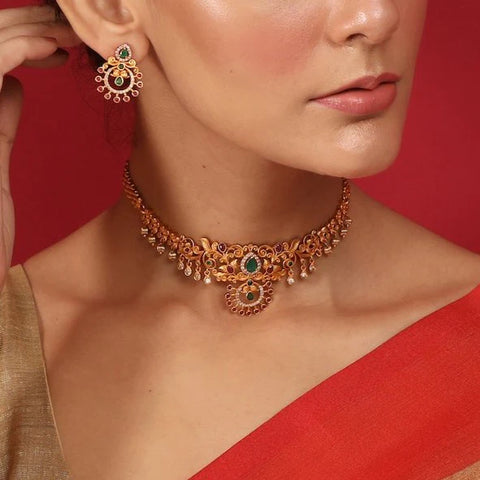 An image of a woman wearing a red saree with an antique choker set