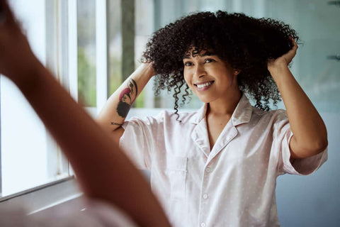 Femme cheveux bouclés qui s'applique du beurre de karité 