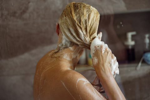 Femme qui se lave les cheveux avec un shampooing antipelliculaire dans sa baignoire