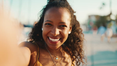 Femme souriante face à la caméra cheveux bouclés comment hydrater cheveux