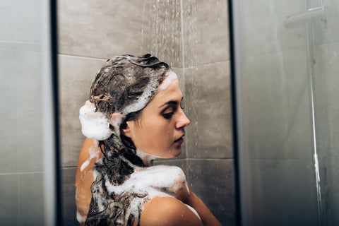 Femme qui se lave les cheveux avec un shampoing antipelliculaire en pharmacie