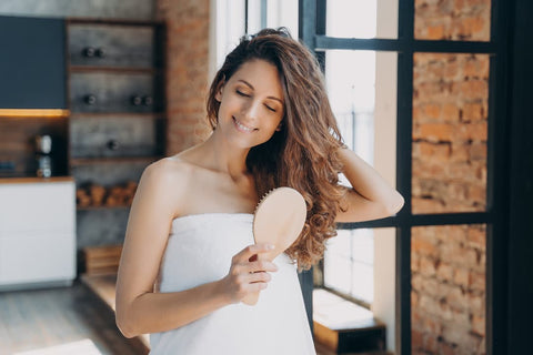 Femme se brosse les cheveux avec une brosse lissante pour éviter les frisottis