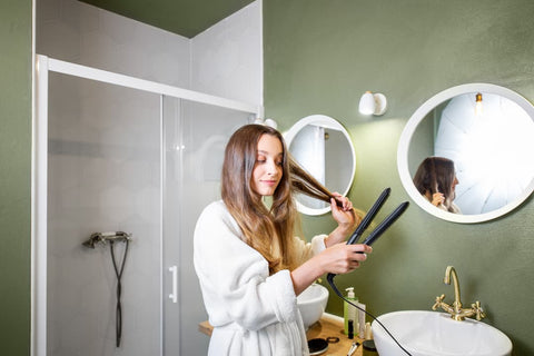 Femme dans salle de bain se lisse les cheveux avec un lisseur au lieu d'une brosse lissante