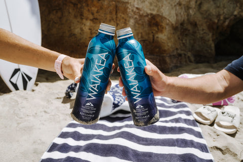 Two people cheersing with waiakea water 