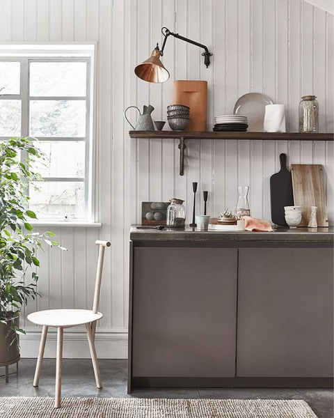 Kitchen setting with white chair against brown counter, displaying an array of rustic kitchen ware