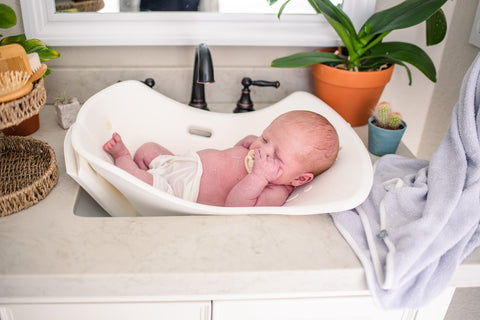 baby in a puj.com tub in a sink
